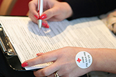 Foto: Frau füllt den Anamnesebogen des Blutspendedienstes aus - Ausschnitt der Hände und des Bogens.